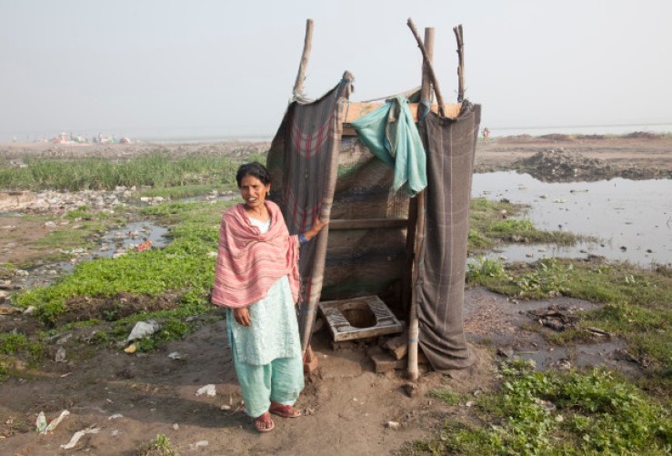 INDIA / New Delhi / 5 March 2011 A woman stands outside a makeshift individual toilet built by a resident, in a public area in front of their home, in a slum colony on the bank of the Yamuna river in the Batla House locality of New Delhi.